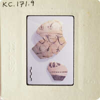 Photograph of ancient pottery shards on white surface.