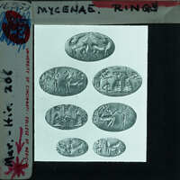 A collection of ancient rings with various designs and symbols on them, displayed behind a glass case.