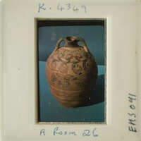 Ancient vase with intricate designs, photographed on a blue surface.