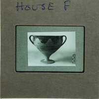 Reassembled two handled cup in profile on table.