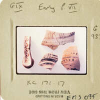 Pile of ancient pottery shards with intricate designs on white surface.