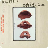 Three ancient clay objects on display, possibly from archaeological excavation.