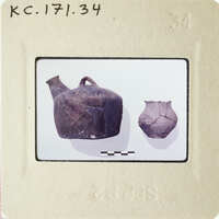 Photograph of ancient pottery on display, including a large jug and two smaller vases.