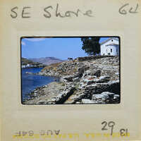 Picture of a coastal landscape with stone walls and water with white building on hill.