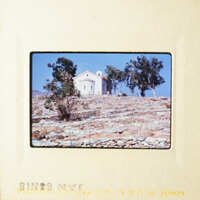 A church on top of a hill with trees and blue sky.