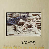The photo shows an archaeological site with stone ruins, and there is a person standing near the ruins.