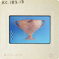 Ancient Greek vase on blue background with visible damage and cracks.