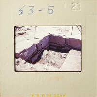 This is an image of a stone-lined pit with dirt at the bottom, possibly part of an archaeological site.