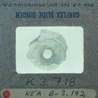 A small, circular object with a hole in the center, placed on a label with handwritten numbers and letters.
