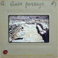 A photograph of a stone-paved road with ruins on either side, enclosed by a white border and labeled with handwritten notes.