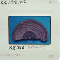 An image of a small, round object with concentric rings, possibly an artifact or a natural sample, placed on a blue background.