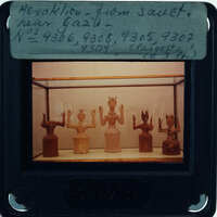 A collection of ancient Egyptian figurines displayed behind glass.