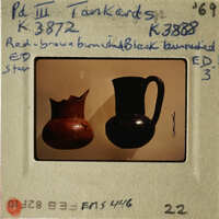 Two vases displayed on a white surface, with one being brown and the other black.