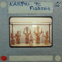 A photograph of ancient Egyptian figurines on display, with a film strip label indicating "KARPHI TREASURES" and the number "66".