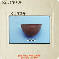 Small brown clay bowl on blue surface with white markings.