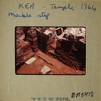 A photograph showing an archaeological site with exposed stone foundations and steps.