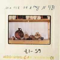 A photograph of an antique slide featuring a shelf with various items, including vases and a pot.