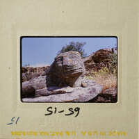 Old photograph of a stone lion sculpture on a rock outcropping.