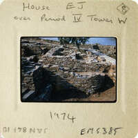 A photograph of an ancient stone structure, possibly ruins, with trees and sky in the background.