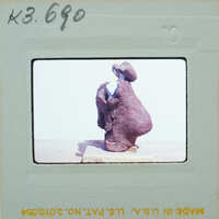 A photograph of a sculpture on display, with a white mat and border around the image.