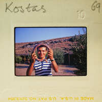 Man holding a round object in front of his face, smiling at the camera.