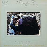 A vintage photo of two people working on a stone structure with handwritten notes.
