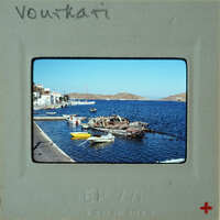 A photograph of a harbor with boats and calm waters, taken from a vintage Polaroid frame.