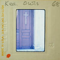 The image shows a photograph of an old wooden door with a cross on it, displayed within a film strip frame.