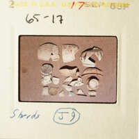 The image shows an archaeological artifact with various pieces, possibly pottery shards, on a table.