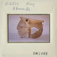 Broken ancient vase with intricate designs, displayed on white surface.