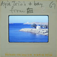 Picture of a scenic coastal landscape with blue water, land and buildings.