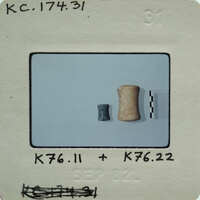 Two small objects, possibly beads or jewelry, on a white surface.