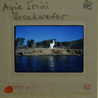A vintage photograph of a church by the water with trees and mountains in the background, displayed on an old film strip.