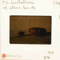 Old photograph of stone bowls on display, with one prominently featured in focus.