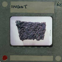 Close-up image of a rock with various textures and colors, captured through a magnifying glass or microscope.