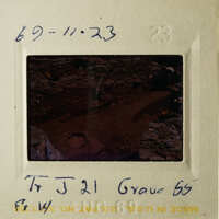 The photo shows a vintage black and white photograph of a rocky landscape with a dark, mysterious cave entrance.