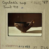 Ancient Greek cup with handle, displayed on a table.