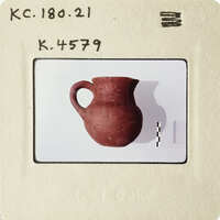 An antique clay pot with handles and a spout, displayed against a white background.