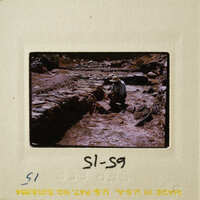 A man wearing a hat, working on stone ruins.