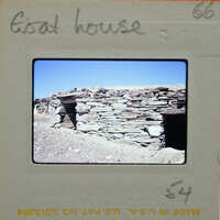 A stone hut with a doorway, sitting on a dry landscape.