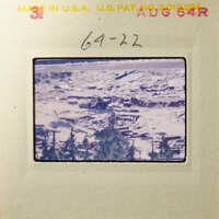 Aerial view of a desert landscape with scattered vegetation and debris, captured on an old photograph.