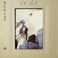 A rocky landscape with a dark crevasse and a clear sky.