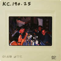 A vintage photo of a group of people enjoying drinks and conversation around a table. Catalog number KC.190.25