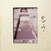 Old photograph showing a dirt path with vegetation and rocks, possibly an archaeological site.