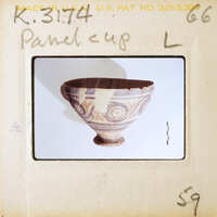 Ancient ceramic bowl with intricate patterns and a handle, displayed on a white surface.