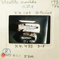 Old rusted metal object with visible wear and tear, photographed on a dark surface.