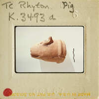 A clay sculpture of an animal, possibly a dog, displayed on a stand.