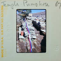 Assortment of stone walls with hose running along the top of one.