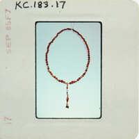 Red bead necklace with tassel on a white background.