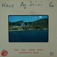 A vintage photograph of a coastal village with a church and mountains in the background, displayed on an old film strip.